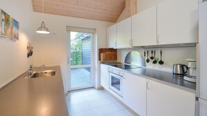 Eine moderne Küche mit weißen Schränken, Edelstahlgeräten und einem großen Fenster.