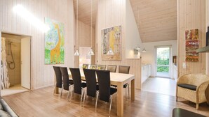 Ein geräumiges Zimmer mit Holzbalkendecke, einem Esstisch mit Stühlen und Kunstwerken an den Wänden.