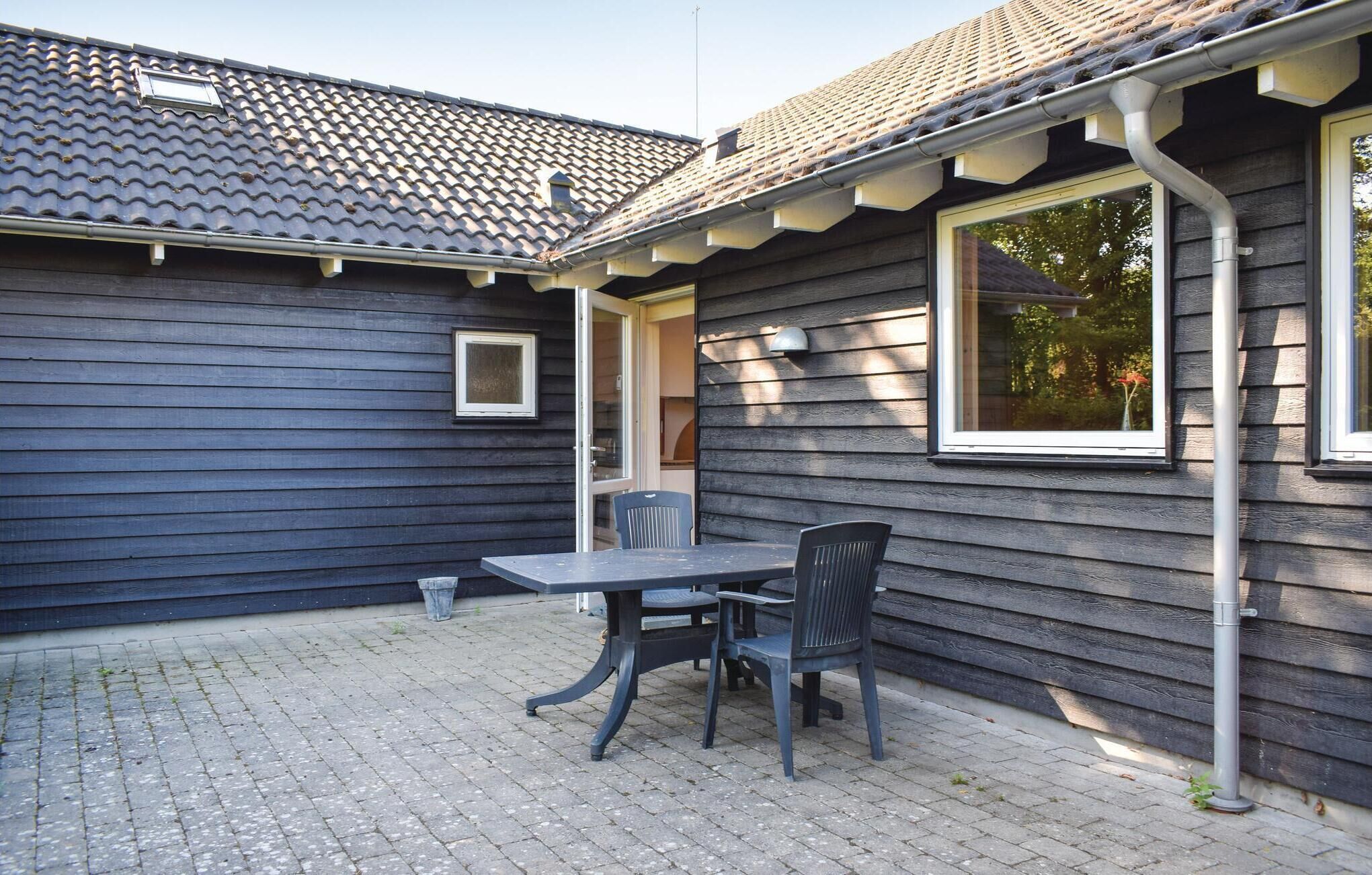 A patio with a table and chairs, a window, and a door leading to an interior space.