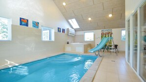 Ein Hallenbad mit Rutsche, Whirlpool und einer Decke mit Oberlichtern.