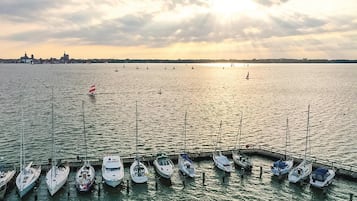 Ein Yachthafen mit mehreren angedockten Booten, eine Stadtansicht im Hintergrund und ein Sonnenuntergang über dem Wasser.