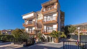 Un immeuble résidentiel à plusieurs étages, doté de balcons, d’une entrée sécurisée et entouré de verdure.