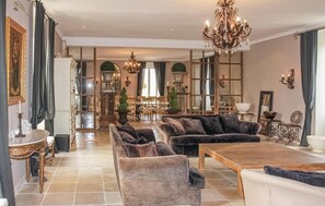 A spacious living room with a chandelier, plush sofas, and a dining area. - Sublime château avec piscine (Pont Saint Esprit)