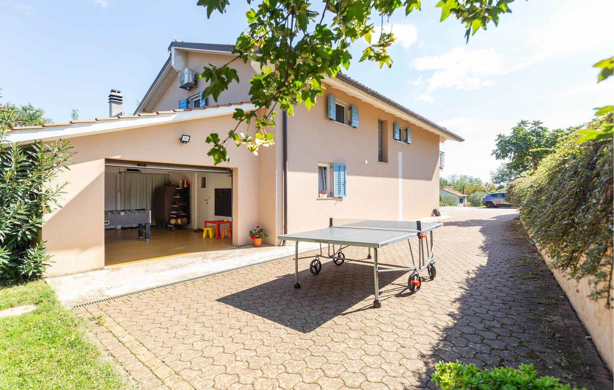 Une maison à deux étages avec une table de ping-pong sur l’allée.