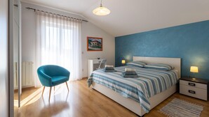 Quarto com cama, escrivaninha, cadeira e luminária.