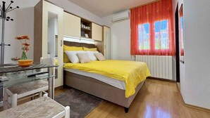 A bedroom with a bed, bedside table, chair, and a window with curtains.