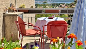 A terrace with a table and chairs, overlooking a scenic landscape.