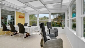 A sunroom with a dining table and chairs, large windows, and a view of the outdoors. - Gorgeous home in Hejls with WiFi (Hejls)