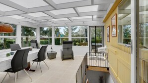 A sunroom with a dining area, large windows, and a view of the outdoors. - Gorgeous home in Hejls with WiFi (Hejls)