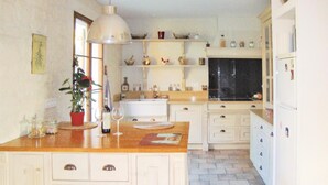 Una cocina con armarios blancos, encimera de madera, un lavabo y una ventana.