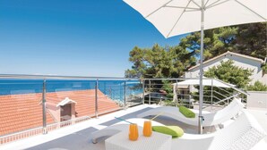 Terraza en la azotea con piscina, mobiliario exterior blanco y una sombrilla grande.