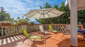 Eine Terrasse mit Tisch, Stühlen und Sonnenschirm.