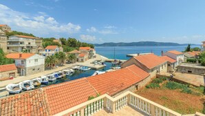 Un pueblo costero con arquitectura tradicional, un puerto deportivo con barcos y una vista despejada del mar.