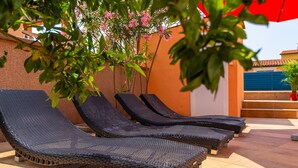 A row of dark wicker lounge chairs aligned against a wall with a tiled floor. - Lovely home in Betiga (Betiga)