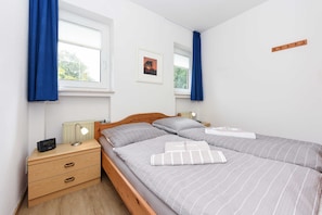 A bedroom with two beds, a nightstand, a lamp, and a framed picture on the wall.