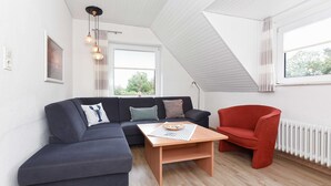 A modern living room with a dark blue sectional sofa, a red armchair, and a wooden coffee table.
