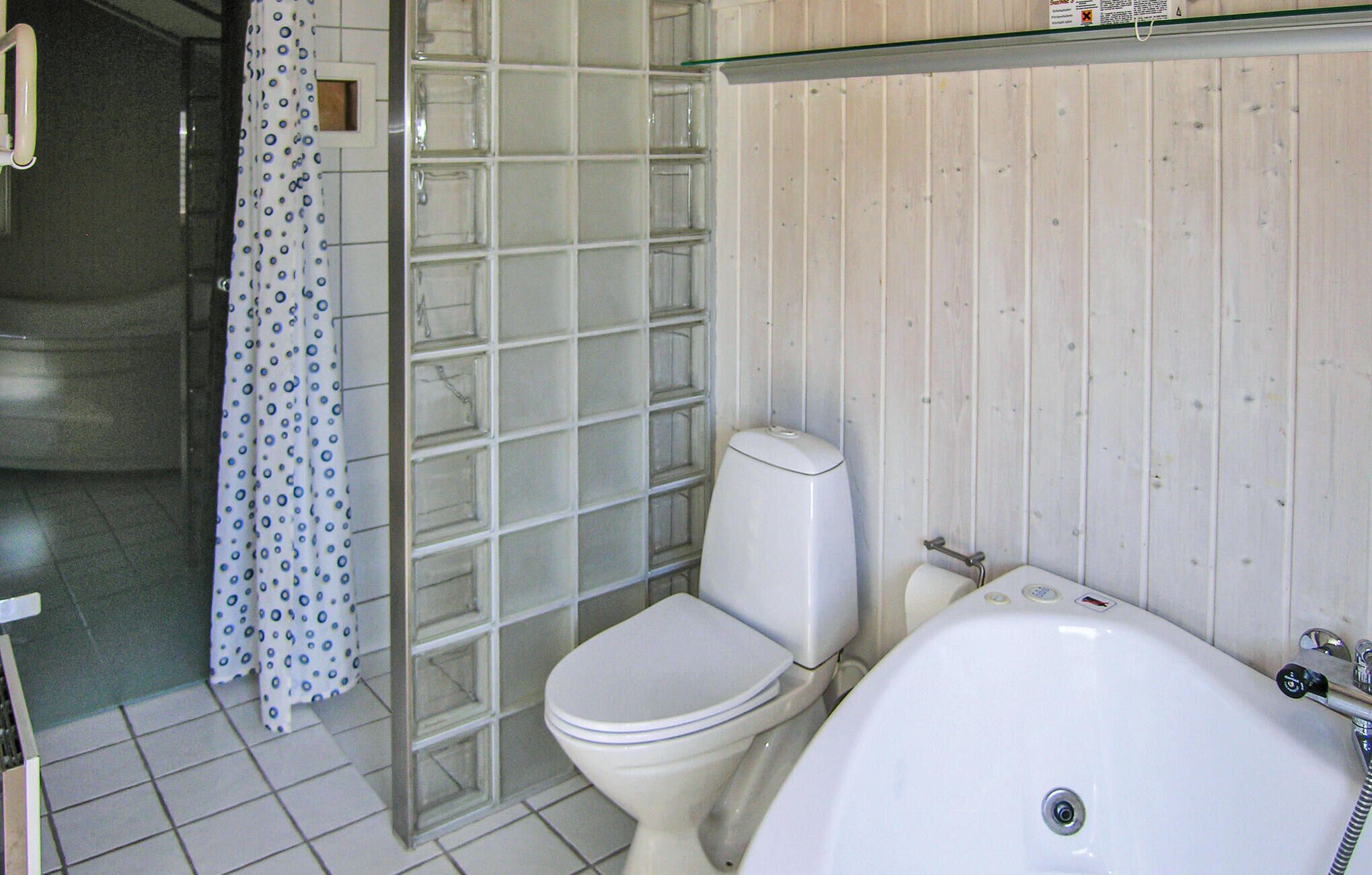 Et badeværelse med toilet, brusekabine i glas og badekar.