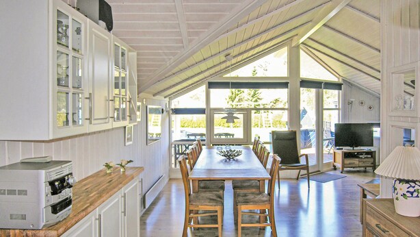 Un'ampia cucina con zona pranzo, ampie finestre e televisione nella sala.