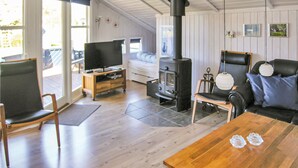 Un accogliente soggiorno con un tavolo di legno, un divano, una TV su un mobiletto e un camino, oltre a un balcone con vista.