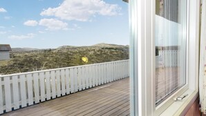 Een balkon met een witte balustrade, met uitzicht op een glooiend landschap.