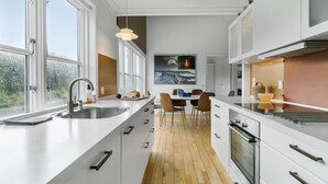 Eine moderne Küche mit weißen Schränken, einem großen Fenster und einem Essbereich mit Tisch und Stühlen.