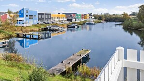 Ein ruhiger Fluss mit vertäuten Booten, umgeben von farbenfrohen Gebäuden und einer Holzsteganlage.