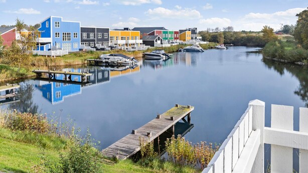 Een rustige rivier met aanmerende boten, omgeven door kleurrijke gebouwen en een houten steiger.