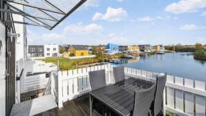 Blick auf einen Fluss von einer Terrasse mit Tisch und Stühlen, mit Blick auf bunte Häuser und Boote auf dem Wasser.