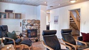 A cozy living room with a stone fireplace, leather chairs, a wooden coffee table, and a staircase leading upstairs. - Pet friendly home in Dølemo with sauna (Dølemo)
