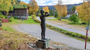 A statue of a person on a pedestal by a road in a rural area with houses and trees. - Pet friendly home in Dølemo with sauna (Dølemo)
