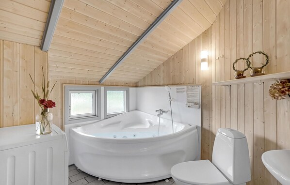 A modern bathroom with a freestanding bathtub, a toilet, and a window. - Amazing home in Hvide Sande with sauna (Hvide Sande)