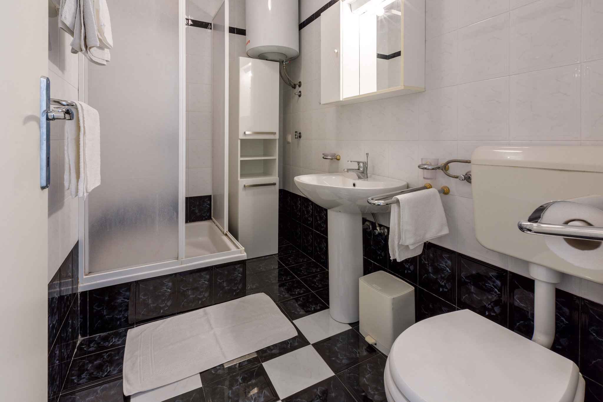 Une salle de bain équipée d’une douche, d’un lavabo, de toilettes et d’un miroir.