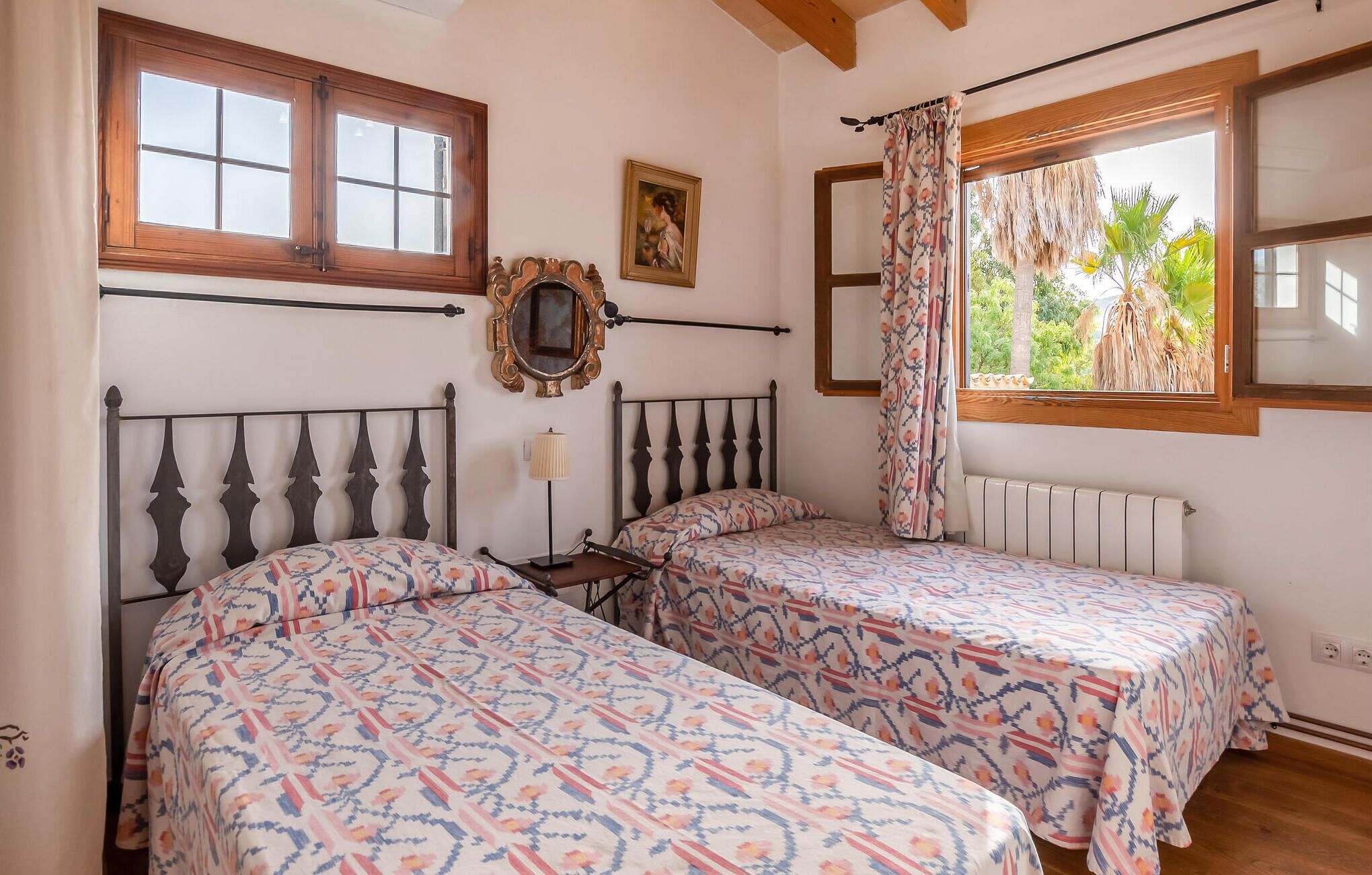 Een kamer met twee bedden, een spiegel en een raam met gordijnen.