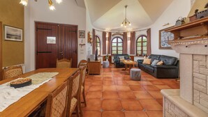 A spacious living area with a fireplace, a dining table with chairs, and a sofa. - Amazing home in Belavici with sauna (Belavici)
