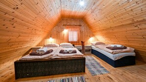 Un dormitorio acogedor en el desván con dos camas, paredes de madera y techo inclinado.
