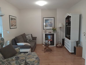 A living room with a sofa, a coffee table, a fireplace, a television, and a lamp.