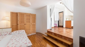 A bedroom with a bed, wooden wardrobe, and a bathroom visible through a doorway.