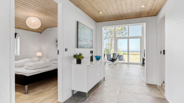 A modern bedroom with a bed, bedside table, and a view of the outdoors.