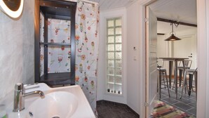 A bathroom with a white sink, a mirror, and a window with frosted glass.