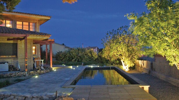 Una casa tradicional japonesa con fachada de madera, tejado de tejas y una pequeña piscina al aire libre.