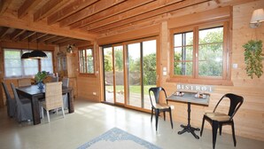 Un interior de madera con zona de comedor, un letrero de bistró y ventanas grandes.