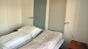 A single bed with white bedding in a room with plain walls.