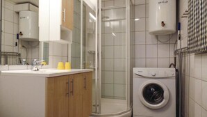 A modern bathroom with a shower, a sink, and a washing machine.