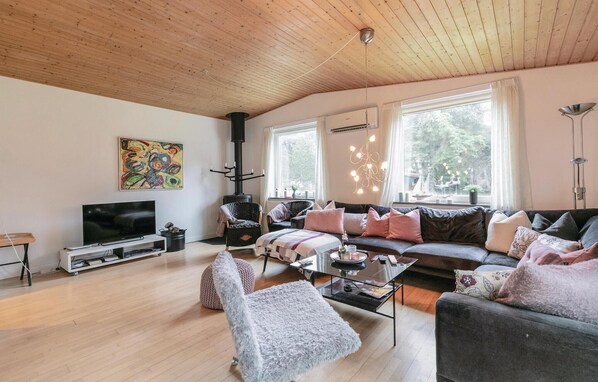 Un salon confortable avec un grand canapé, un téléviseur, une cheminée et de grandes fenêtres.