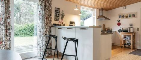 Een moderne keuken met een centraal eiland, barstoelen, een magnetron en uitzicht op de omgeving.
