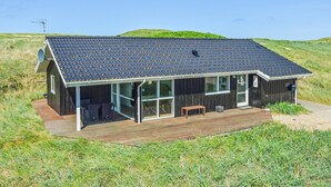 A modern house with a dark roof, large windows, and a wooden deck. - Nice home in Harboøre with sauna (Harboøre)