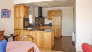 A kitchen with wooden cabinets, a built-in oven, and a coffee maker. - 2 bedroom beautiful home in Kerlouan (Kerlouan)
