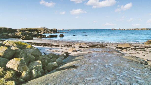 A rocky beach with clear blue water and a distant rocky outcrop. - 2 bedroom beautiful home in Kerlouan (Kerlouan)