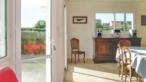 A dining area with a table and chairs, a window with a view of greenery, and a radio on the counter. - 2 bedroom beautiful home in Kerlouan (Kerlouan)