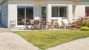 A house with a patio area featuring a table and chairs, a gravel driveway, and a grassy lawn. - 2 bedroom beautiful home in Kerlouan (Kerlouan)